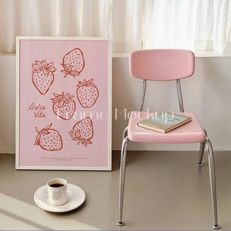 Puede incluir: Una impresi&oacute;n enmarcada con un fondo rosa y dibujos de l&iacute;nea roja de fresas. El texto "Dolce Vita" est&aacute; escrito en la esquina inferior izquierda. La impresi&oacute;n est&aacute; colgada en una pared junto a una silla rosa con un libro en el asiento.
