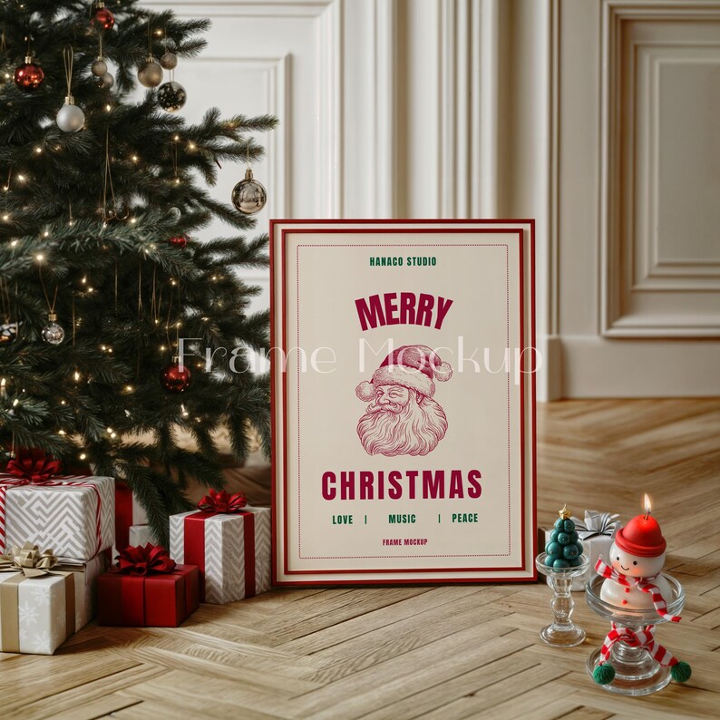 K&ouml;nnte beinhalten: Ein gerahmter Weihnachtsdruck mit einer roten und wei&szlig;en Illustration des Weihnachtsmanns. Der Druck lautet "Frohe Weihnachten" und "Hanako Studio" in gr&uuml;nem Text. Der Rahmen ist rot und wei&szlig; und steht auf einem Holzboden vor einem Weihnachtsbaum.