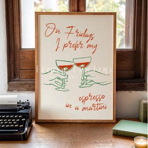 May include: A framed print with a white background and red text that reads "On Fridays I prefer my espresso in a martini". The print features two red martini glasses with green stems, held by two hands.