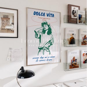 May include: A framed poster with a white background and a green illustration of a woman wearing a hat and a white shirt. The poster has the text "DOLCE VITA" in blue and red text. The text "A woman's laughter is the music of summer" is in smaller blue text. The text "summer days are a canvas for women's dreams" is in blue text.