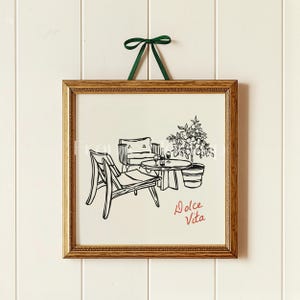 Puede incluir: Un dibujo en blanco y negro de una escena de patio con dos sillas, una mesa y un &aacute;rbol de c&iacute;tricos en maceta. El texto "Dolce Vita" est&aacute; escrito en rojo debajo de la mesa.