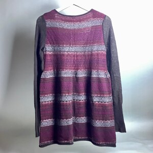 May include: A long-sleeved purple and gray striped sweater with a geometric pattern.