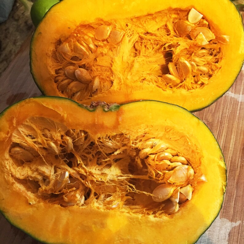 May include: Two halves of a yellow pumpkin with the seeds removed and visible. The pumpkin flesh is a bright orange color.