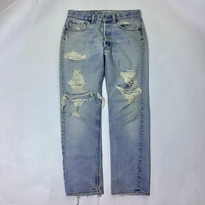 May include: Light blue denim jeans with multiple distressed holes and frayed edges.