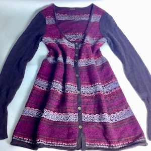 May include: A long-sleeved cardigan with a button-up front and a geometric pattern in shades of purple, pink, and brown. The cardigan has a scoop neck and a slightly flared hem.