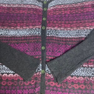 May include: A black and purple striped cardigan with a button-up front. The cardigan has a fair isle pattern with geometric shapes.