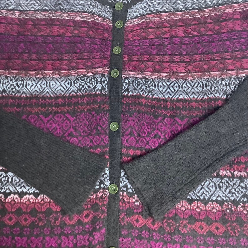 May include: A black and purple striped cardigan with a button-up front. The cardigan has a fair isle pattern with geometric shapes.