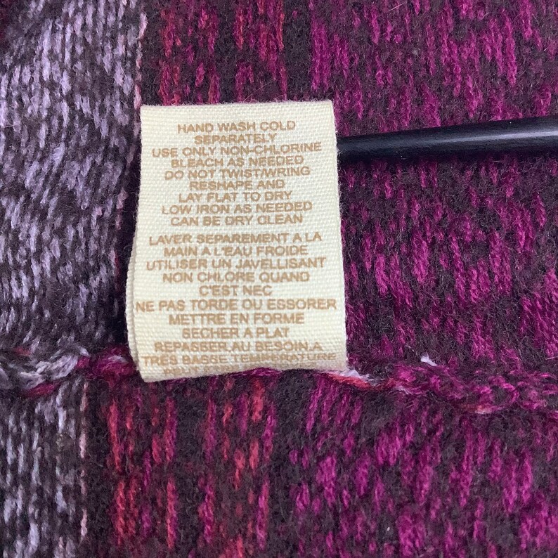 May include: A tan fabric care label with instructions for washing, bleaching, drying, ironing, and dry cleaning. The text is in both English and French.