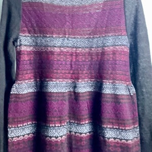 May include: A long-sleeved sweater dress with a purple, pink, and gray geometric pattern. The sleeves are a solid gray color.