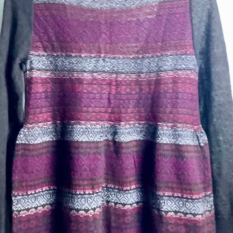 May include: A long-sleeved sweater dress with a purple, pink, and gray geometric pattern. The sleeves are a solid gray color.