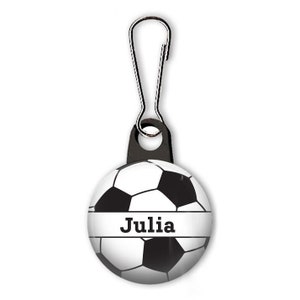 May include: Black and white soccer ball zipper pull with the name "Julia" printed on a white stripe.