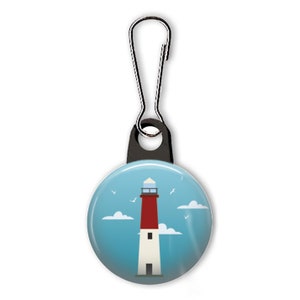 May include: A red and white lighthouse with a blue sky and white clouds. The lighthouse is on a blue button with a black zipper pull.