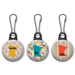 May include: Three zipper pulls with colorful patterned circles, each featuring an outline of the state of Minnesota and a phrase: "You betcha.", "Uff da.", and "Holddish."