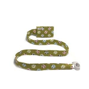May include: A green fabric tube with a soccer ball pattern, featuring a small rectangular pouch and a white plastic piece at the end. The fabric has a repeating pattern of soccer balls in various colors. The text "Tiny Tube" is visible on the pouch.