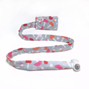 May include: A gray fabric lanyard with a white magnetic clasp and a small gray fabric pouch with the text "TuneTube" and a mushroom pattern.