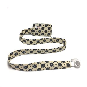 May include: A black and beige patterned lanyard with a black and white badge holder that says "TuneTube" on it. The lanyard has a white breakaway clasp.