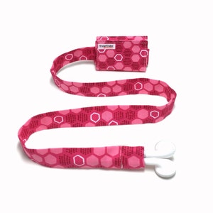 May include: Pink fabric lanyard with a small pink and white patterned pouch that says "TuneTube Originals" and white earbud holders.
