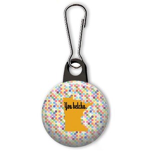 May include: A colorful polka dot button with a yellow outline of the state of Minnesota and the text "You betcha." The button is attached to a black zipper pull.