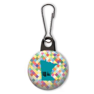 May include: A colorful zipper pull featuring a teal outline of the state of Minnesota with the text "Uff da." on a background of colorful squares.