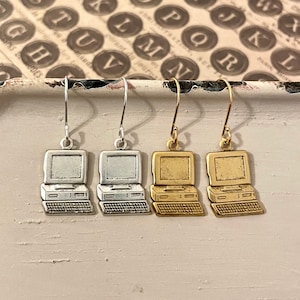 May include: Three pairs of silver and gold earrings shaped like vintage computers. The earrings have a silver, gold, and gold finish.
