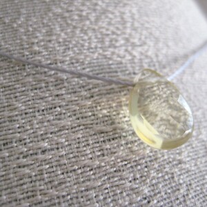 Puede incluir: Un collar delicado con un colgante de piedra preciosa amarilla facetada transparente.