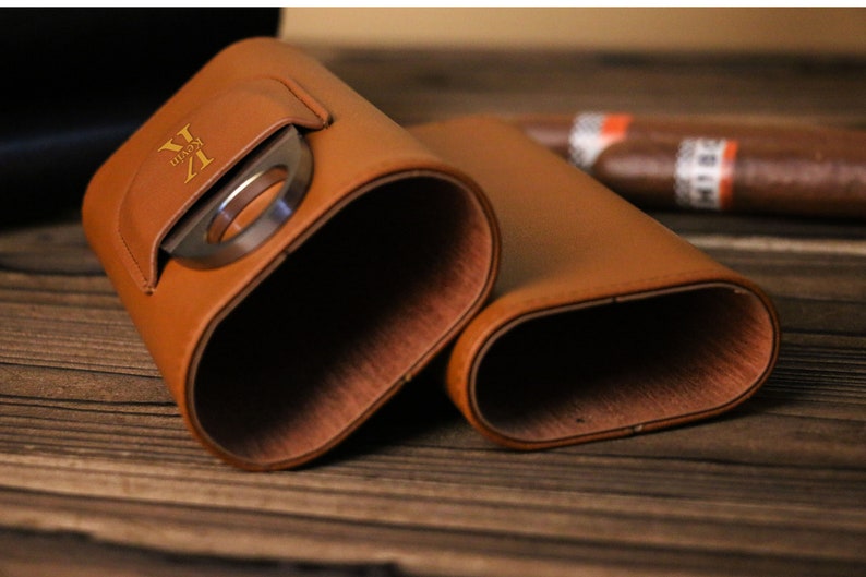 K&ouml;nnte beinhalten: Ein braunes Leder-Zigarrenetui mit integriertem Cutter. Das Etui tr&auml;gt eine goldene Inschrift "V.I.P."