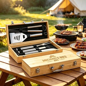 May include: A wooden barbecue tool set in a rectangular bamboo carrying case with metal latches and a handle. The lid is engraved with the text "MICHAEL'S BBQ". Inside, stainless steel grilling utensils including a spatula, fork, and brush are secured.