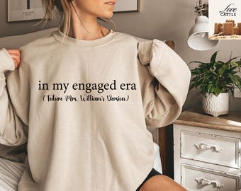 May include: A beige sweatshirt with the text "in my engaged era (Future Mrs. William's Version)" printed on the front.