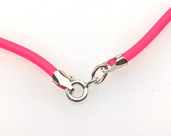 May include: A close-up of a bright pink necklace with a silver clasp. The necklace is made of a flexible, rounded material. The clasp is a simple, secure design, connecting the two ends of the necklace.