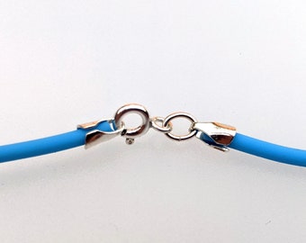 May include: Close-up of a light blue necklace with a silver clasp. The necklace has a simple, minimalist design, with a bright blue cord and a shiny silver clasp. The clasp is a standard lobster claw style.