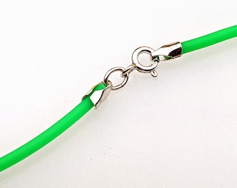 May include: Close-up of a neon green necklace with a silver clasp. The necklace has a bright, vibrant color and a simple, modern design. The clasp is a standard lobster claw style.
