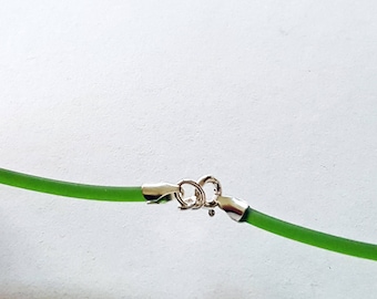 May include: A close-up of a green necklace with a silver clasp. The necklace is a vibrant green color and appears to be made of a flexible material. The clasp is a shiny silver color and is securely fastened.