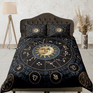 May include: Black and gold duvet cover with a celestial design featuring a sun and moon with zodiac symbols. The duvet cover has a dark blue background with gold accents.
