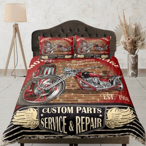 Pode incluir: Conjunto de roupa de cama de motocicleta vermelha, preta e dourada com um design de motocicleta vintage. A roupa de cama apresenta uma motocicleta vermelha com uma bomba de gasolina e o texto "Motorcycle Garage, Custom Parts, Service & Repair, Superior Performance, Est. 1968".