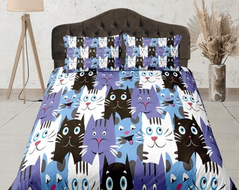 May include: A blue and white bedding set with a cat pattern. The cats are in various poses and have different colored eyes. The bedding set includes a duvet cover and two pillowcases.