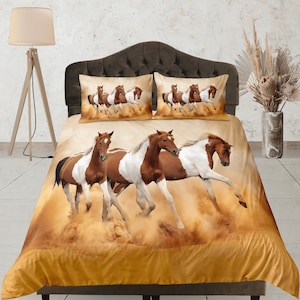 Może przedstawiać: Zestaw pościeli z brązowymi i białymi końmi biegnącymi przez pole piasku. Zestaw zawiera poszewkę na kołdrę i dwie poszewki na poduszki.