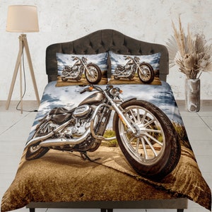 Pode incluir: Um conjunto de roupa de cama marrom, branco e azul com uma motocicleta cromada impressa na capa do edredom e nas fronhas. A motocicleta é do estilo cruiser clássico com uma roda dianteira grande.