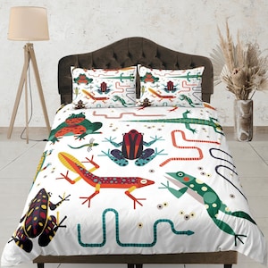 Puede incluir: Bedding blanco con un patrón colorido de rana, lagarto y serpiente. La ropa de cama presenta una variedad de colores verdes, rojos, azules y amarillos.