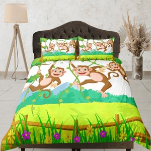 May include: A white and green bedding set with a jungle theme featuring monkeys swinging from vines. The bedding set includes a duvet cover and two pillowcases.