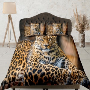 Könnte beinhalten: Ein Bettwäsche-Set in Braun- und Schwarz-Leopard-Muster mit einem großen Leoparden, der auf dem Bett liegt. Das Bettwäsche-Set beinhaltet einen Bettbezug, zwei Kissenbezüge und ein Spannbettlaken.