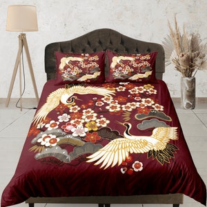 May include: A burgundy duvet cover with a white crane and cherry blossom print. The duvet cover features a repeating pattern of cranes and cherry blossoms in a traditional Japanese style.