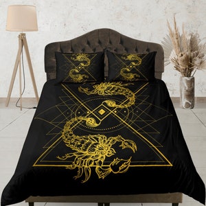 May include: Black and gold bedding set with a geometric design featuring a scorpion. The scorpion is outlined in gold and has a detailed design.