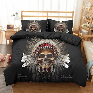 May include: Black and white bedding set with a skull wearing a Native American headdress. The headdress has feathers and beads. The text "Indian Cherokee" is printed on the bedding.