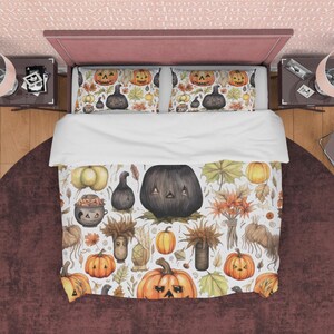 May include: A white duvet cover with a Halloween-themed pattern featuring black and orange pumpkins, leaves, and other autumnal elements. The duvet cover is on a bed with two matching pillowcases.