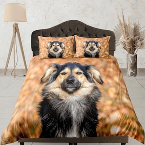Può includere: Un set di biancheria da letto con un cane marrone e nero con un'espressione seria. Il set comprende una federa e due federe per cuscini. La federa ha uno sfondo marrone con un'immagine sfocata di foglie. Le federe per cuscini hanno uno sfondo bianco con un'immagine chiara della testa del cane.