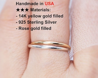 May include: Two thin rings, one gold and one silver, are stacked on a finger. The image includes text that reads "Handmade in USA" and lists materials: 14K yellow gold filled, 925 Sterling Silver, and rose gold filled.