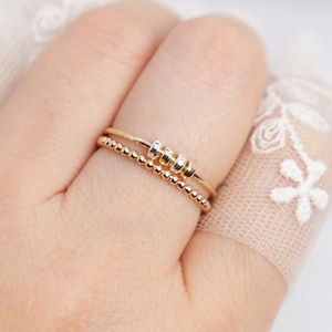 May include: Two gold rings are displayed on a finger. One ring features small, evenly spaced beads, while the other has a smooth band with three mixed-metal beads. The text "Gold - Mixed beads" is visible in the upper left corner.