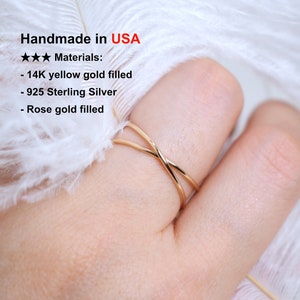 May include: A gold-toned ring with a criss-cross design. The ring is made of 14K yellow gold filled, 925 Sterling Silver, and rose gold filled. Handmade in the USA.