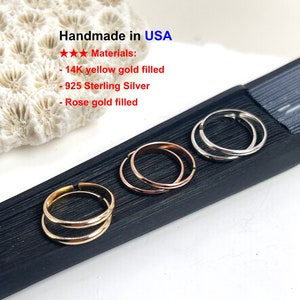 May include: Three rings in yellow gold, rose gold, and sterling silver, each with a double-band design. The rings are displayed on a black surface, with the text "Handmade in USA" and material details visible.