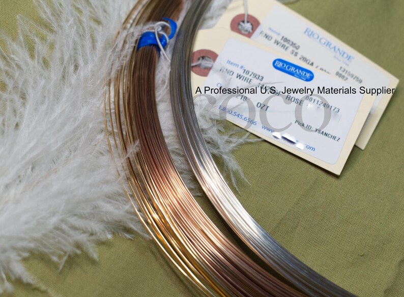 Puede incluir: Primer plano de suministros para la fabricaci&oacute;n de joyas, que incluyen carretes de alambre de color cobre, plata y oro. Tambi&eacute;n se ven una pluma blanca y una etiqueta de Rio Grande, un proveedor de materiales para joyer&iacute;a. La etiqueta dice "END WIRE SS 20GA".